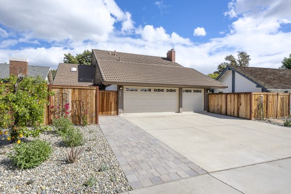 Double garage with fence, brick pathway, and small garden to the side