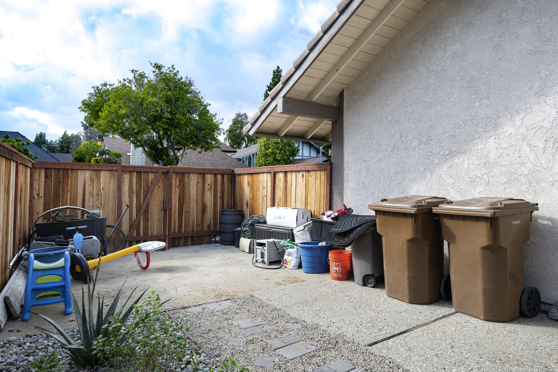 Outdoors storage area with trash cans and latched fence entrance