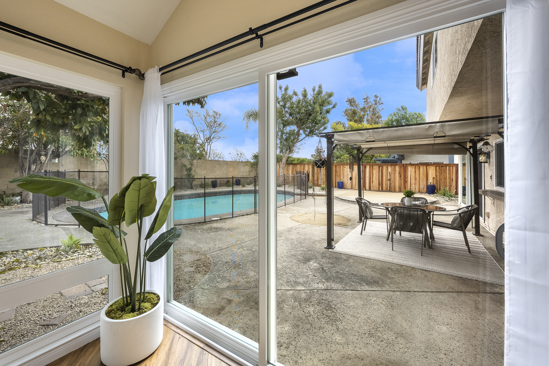 View of backyard pool and sitting area with overhang through corner glass windows