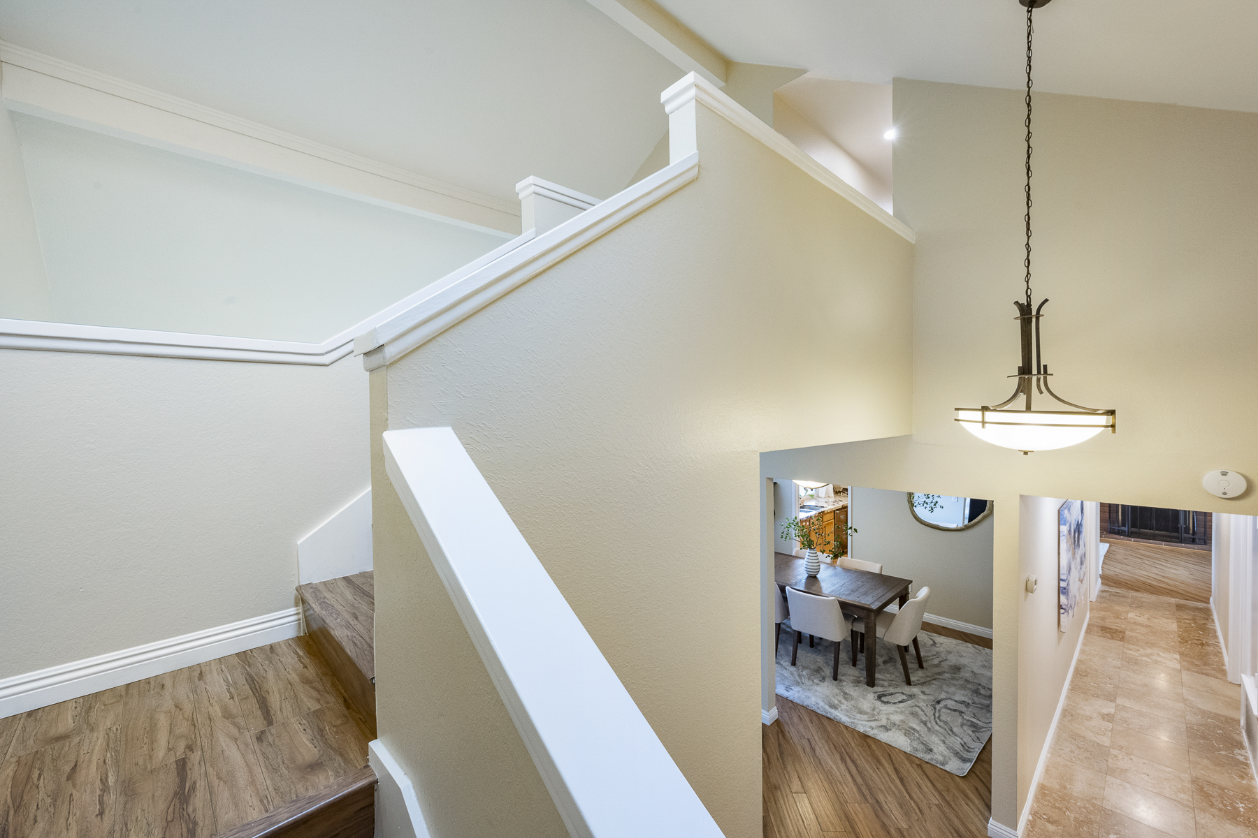 Side view of stairs with hanging light fixture and view of dining room