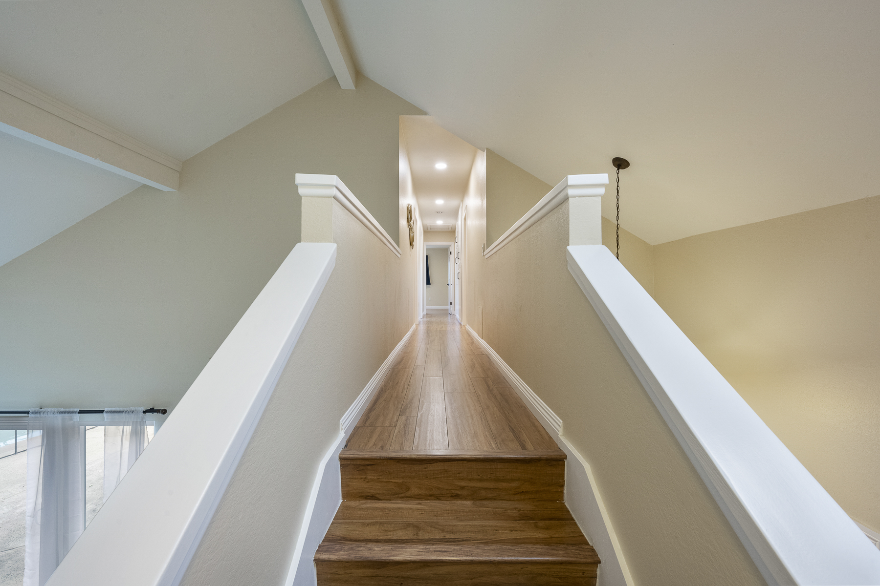 Long hallway with hardwood floors ending in stairs