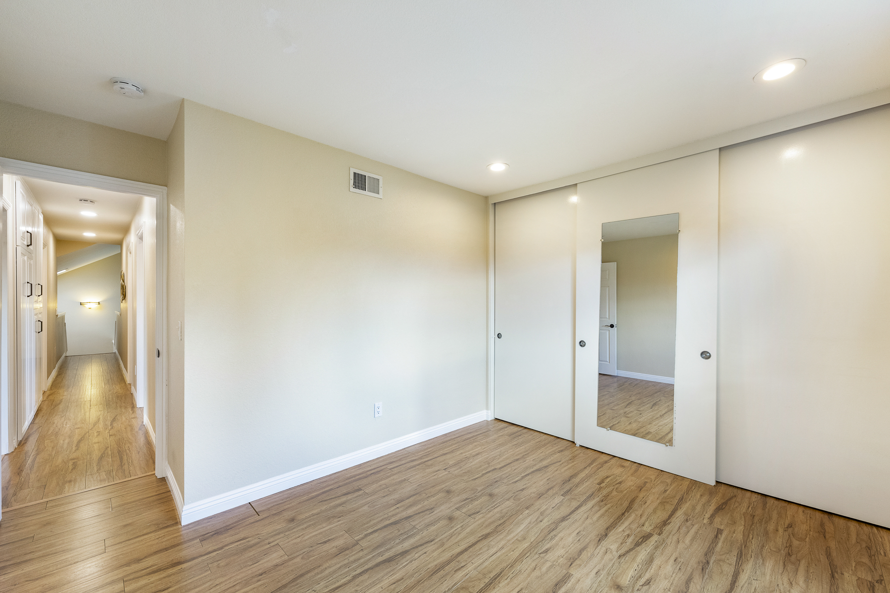 Corner with sliding door, hardwood floors, and hallway